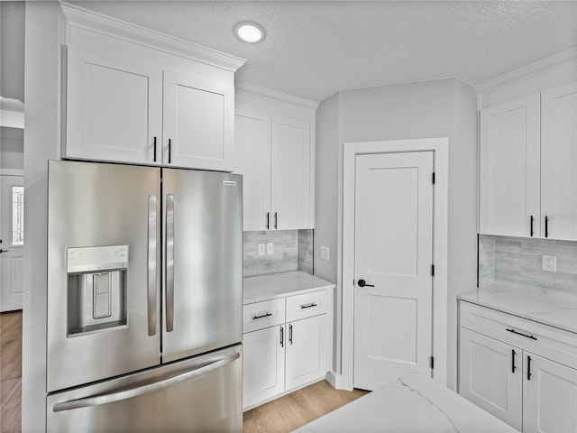 kitchen featuring light stone counters, backsplash, white cabinets, and stainless steel fridge with ice dispenser