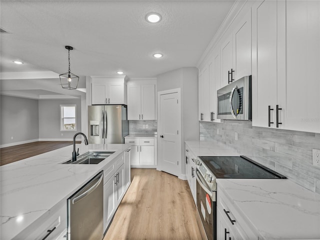 kitchen featuring light stone counters, a sink, white cabinets, hanging light fixtures, and appliances with stainless steel finishes