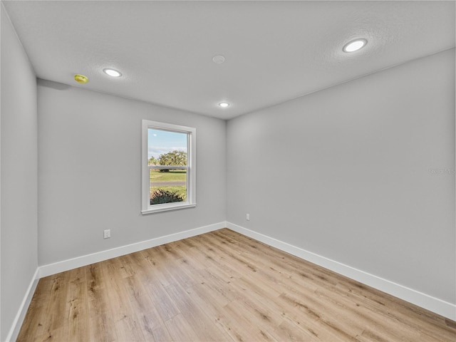 spare room with light wood-type flooring, baseboards, a textured ceiling, and recessed lighting