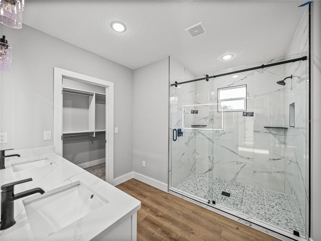 full bath with double vanity, a marble finish shower, visible vents, and a sink