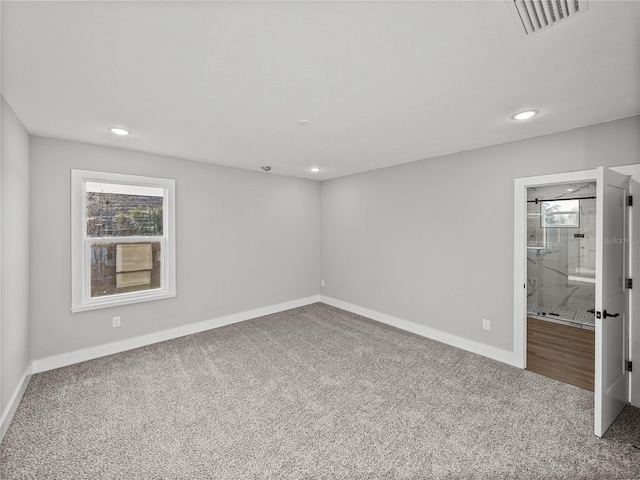 carpeted spare room featuring baseboards, visible vents, and a healthy amount of sunlight