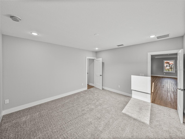 spare room featuring recessed lighting, carpet flooring, visible vents, and baseboards