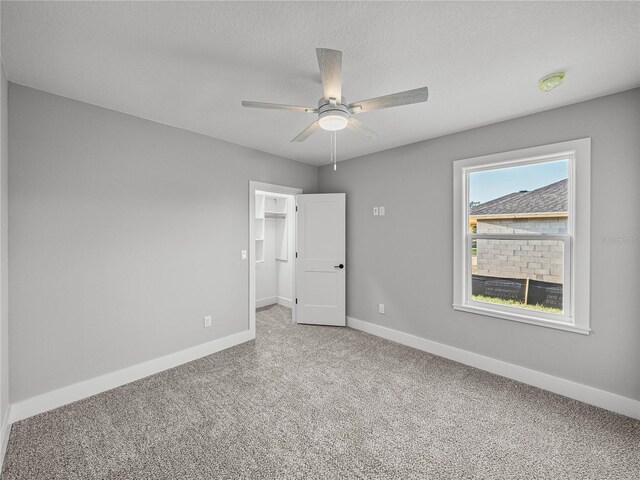 carpeted spare room with a ceiling fan, baseboards, and a textured ceiling