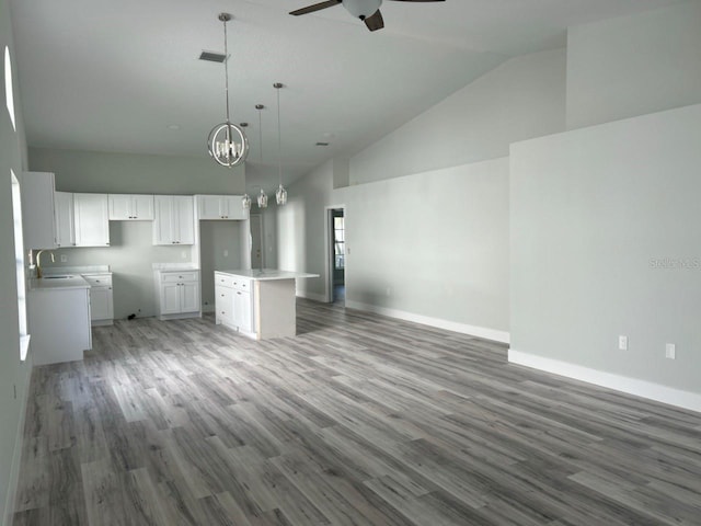 kitchen featuring white cabinets, open floor plan, a center island, light countertops, and pendant lighting