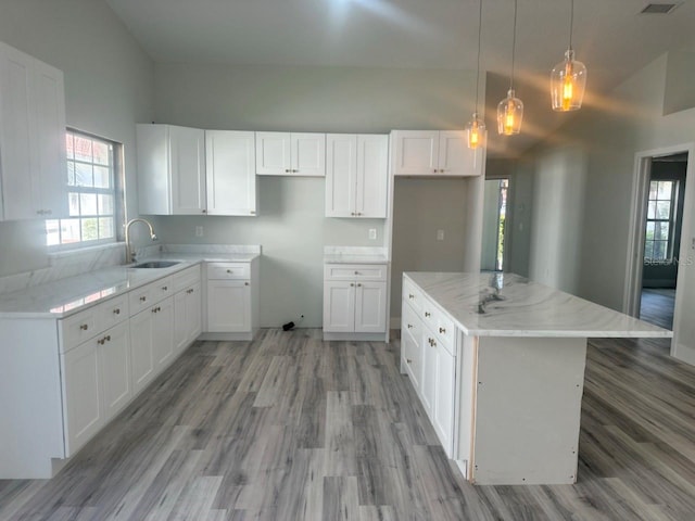 kitchen featuring a center island, white cabinetry, a sink, and decorative light fixtures