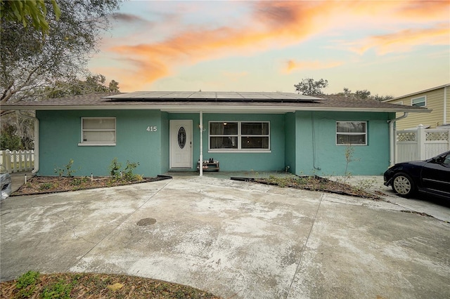 view of front of property featuring a porch, solar panels, fence, and stucco siding