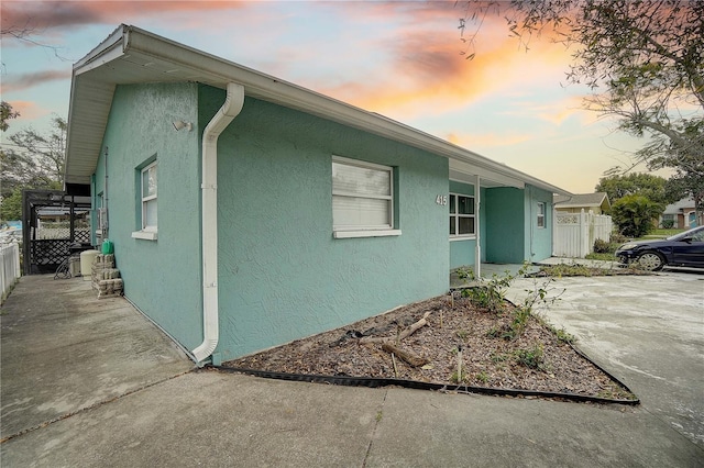 view of side of property featuring a patio area, fence, and stucco siding