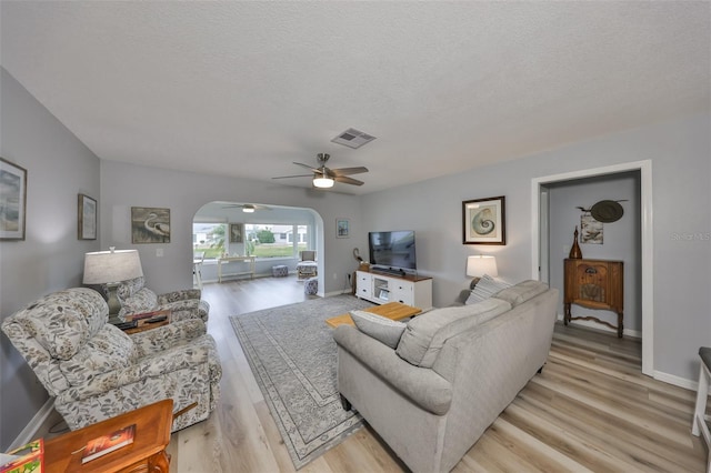 1805 Columbine Pl, Sun City Center, FL 33573 - living area with light wood finished floors, visible vents, arched walkways, baseboards, and a textured ceiling