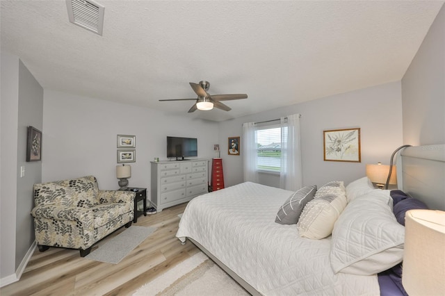 1805 Columbine Pl, Sun City Center, FL 33573 - bedroom with light wood finished floors, visible vents, baseboards, ceiling fan, and a textured ceiling