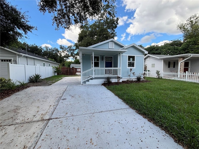 view of front of house featuring a porch, driveway, a front lawn, and fence