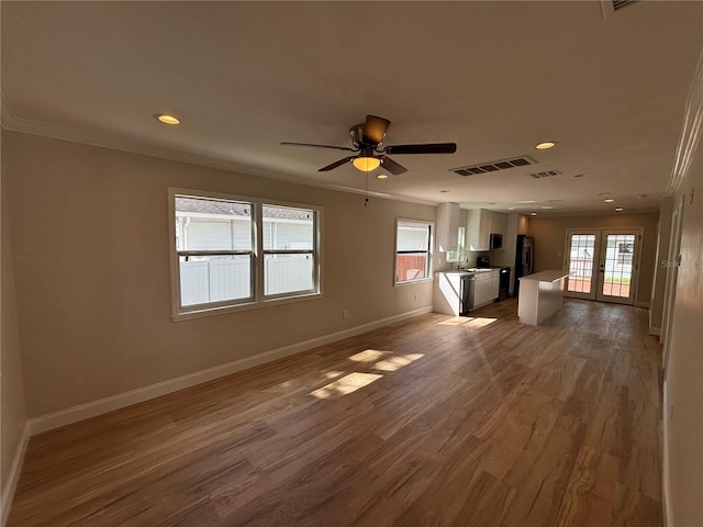 unfurnished living room with visible vents, crown molding, baseboards, and wood finished floors