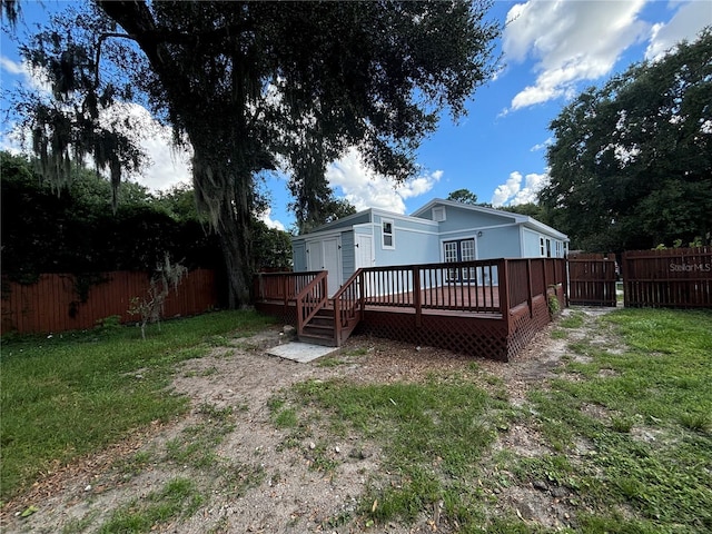 rear view of house featuring a fenced backyard, a yard, and a wooden deck