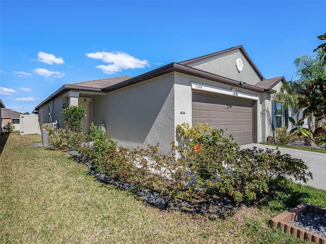 view of side of home featuring a garage, driveway, a lawn, and stucco siding