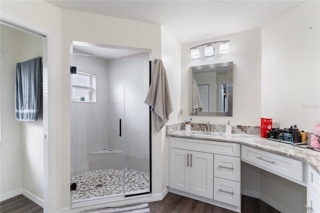 bathroom with a stall shower, baseboards, wood finished floors, and vanity