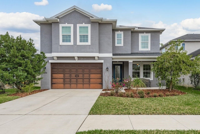 view of front of house with a garage, driveway, a front yard, and stucco siding