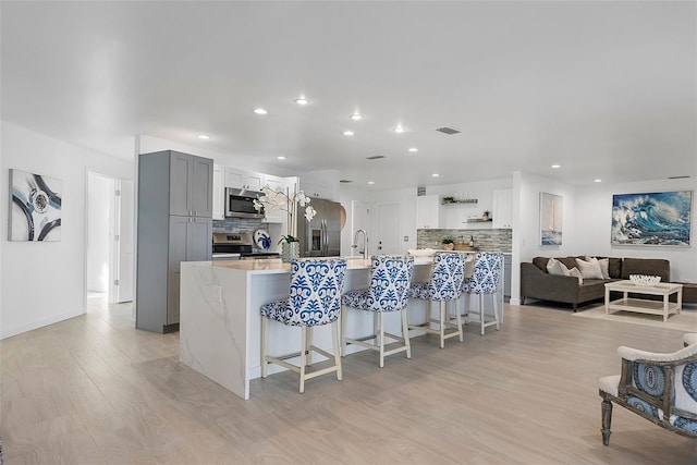 1984 Kansas Ave NE, Saint Petersburg, FL 33703 - kitchen featuring visible vents, a breakfast bar, gray cabinets, stainless steel appliances, and backsplash