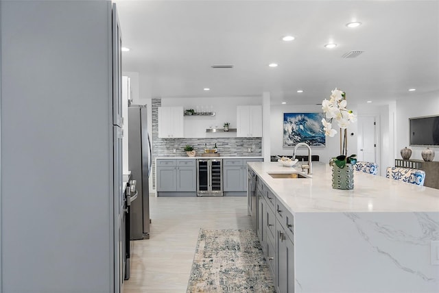 1984 Kansas Ave NE, Saint Petersburg, FL 33703 - kitchen featuring open shelves, gray cabinets, freestanding refrigerator, a sink, and light stone countertops