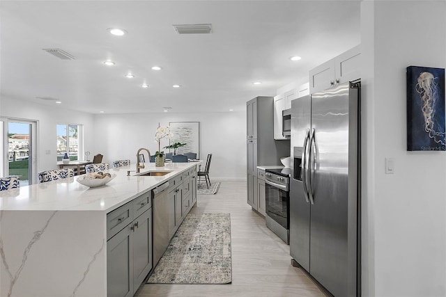 1984 Kansas Ave NE, Saint Petersburg, FL 33703 - kitchen with gray cabinetry, stainless steel appliances, a sink, visible vents, and light stone countertops
