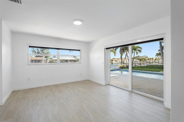 1984 Kansas Ave NE, Saint Petersburg, FL 33703 - empty room with plenty of natural light, light wood-style flooring, and baseboards
