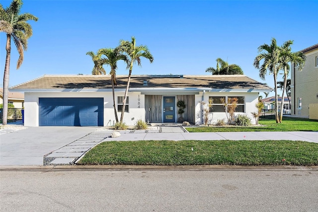 1984 Kansas Ave NE, Saint Petersburg, FL 33703 - view of front of home featuring a front lawn, concrete driveway, an attached garage, and stucco siding