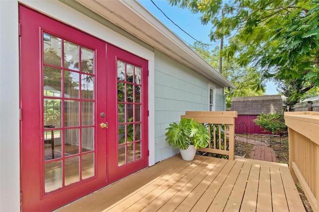 wooden terrace featuring a shed, an outdoor structure, and french doors