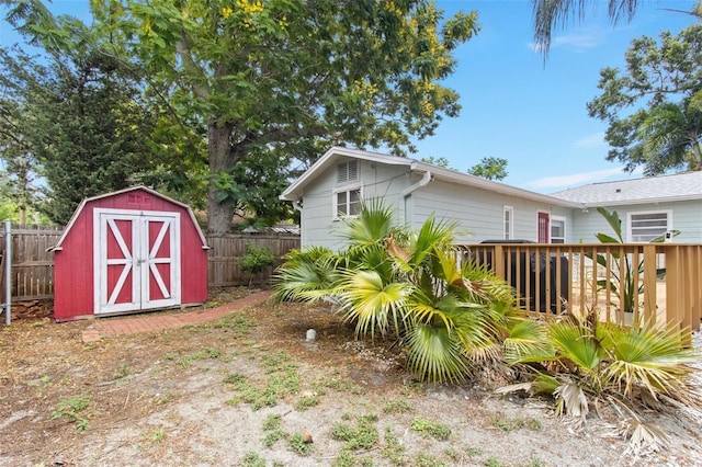 view of yard featuring an outdoor structure, a deck, a storage shed, and fence