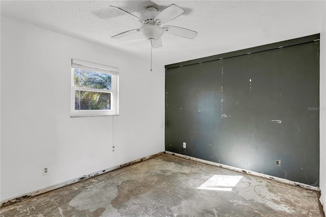 spare room with a textured ceiling, a ceiling fan, and concrete flooring