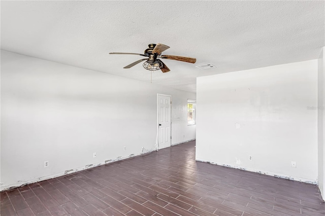 empty room with a textured ceiling, dark wood-style flooring, visible vents, and a ceiling fan