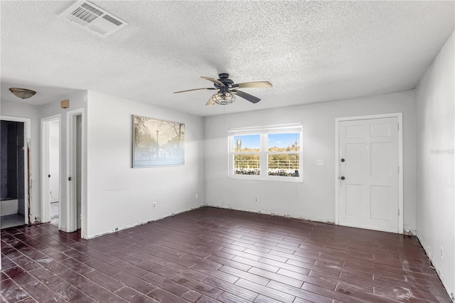 unfurnished room featuring dark wood-type flooring, visible vents, ceiling fan, and a textured ceiling