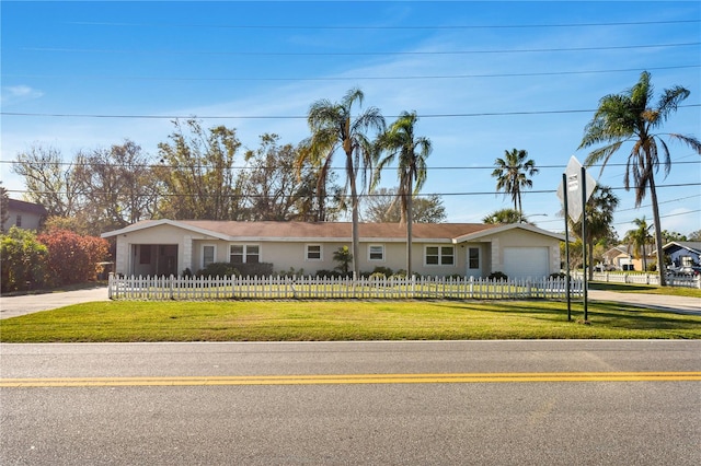 ranch-style house with a fenced front yard, concrete driveway, a front lawn, and a garage