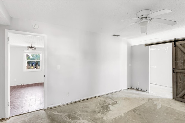 spare room with concrete floors, a textured ceiling, and a barn door