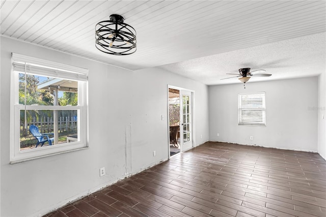 spare room with ceiling fan, a textured ceiling, and dark wood-style floors