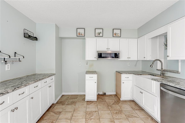 kitchen featuring light stone countertops, appliances with stainless steel finishes, white cabinets, and a sink