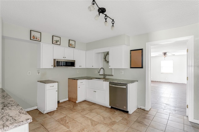 kitchen featuring a ceiling fan, appliances with stainless steel finishes, a textured ceiling, white cabinetry, and a sink