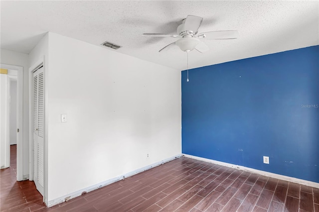 unfurnished room featuring baseboards, visible vents, a ceiling fan, a textured ceiling, and wood finish floors