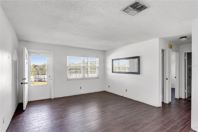 spare room with a textured ceiling, dark wood-type flooring, and visible vents