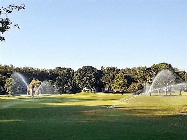 view of property's community with view of golf course and a lawn