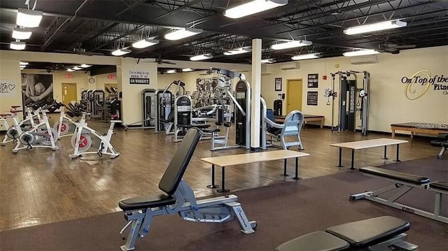 workout area with wood finished floors and an AC wall unit