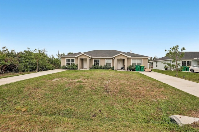 ranch-style house featuring a front lawn, concrete driveway, and stucco siding