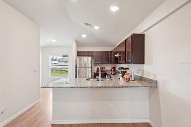 kitchen featuring a peninsula, appliances with stainless steel finishes, visible vents, and light stone counters