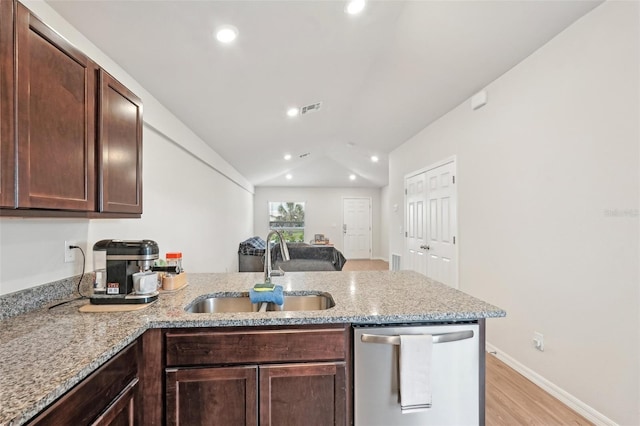 kitchen featuring light stone counters, stainless steel dishwasher, a sink, and visible vents