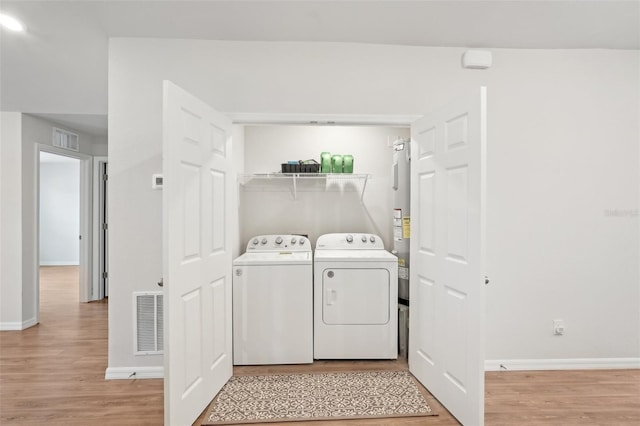 laundry area with light wood-type flooring, laundry area, visible vents, and washer and clothes dryer