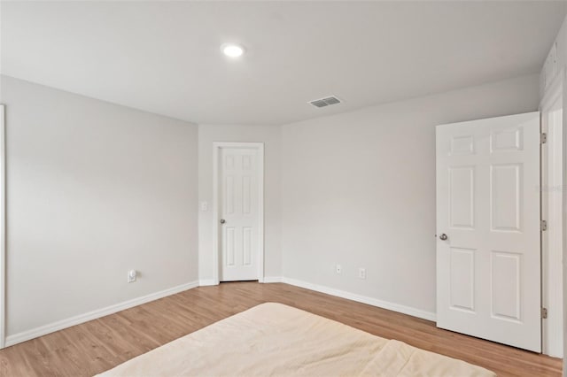 unfurnished bedroom featuring light wood finished floors, baseboards, and visible vents