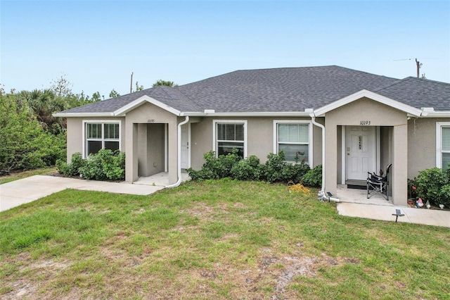 ranch-style home featuring a shingled roof, a front yard, and stucco siding