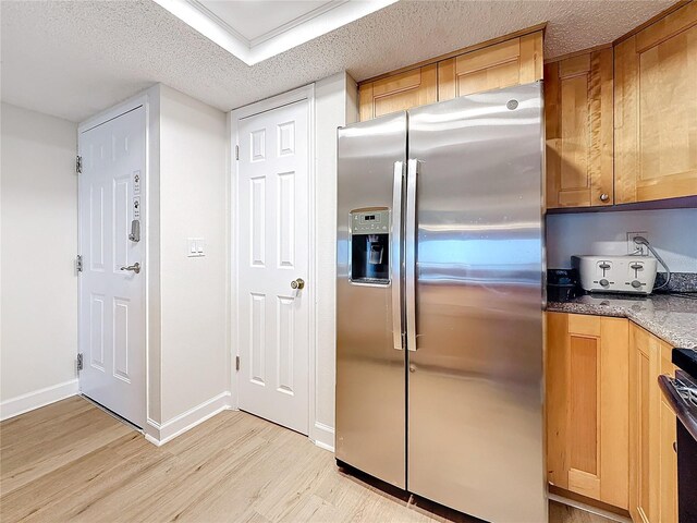 kitchen featuring stainless steel fridge with ice dispenser, light wood-style flooring, stone countertops, a textured ceiling, and baseboards