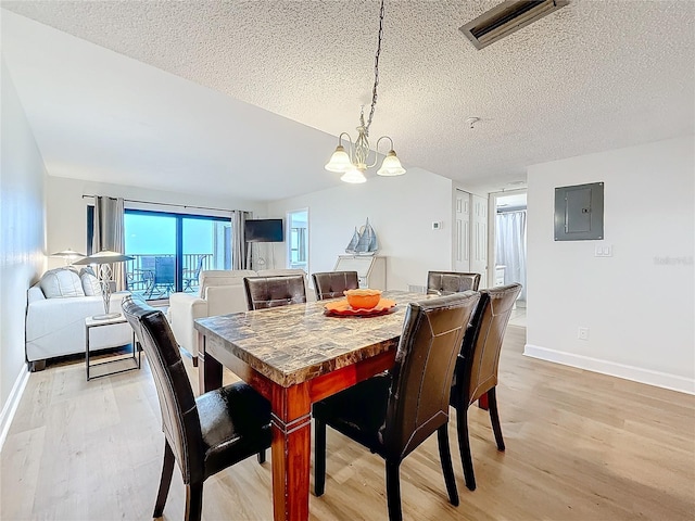 dining space featuring baseboards, electric panel, and light wood finished floors