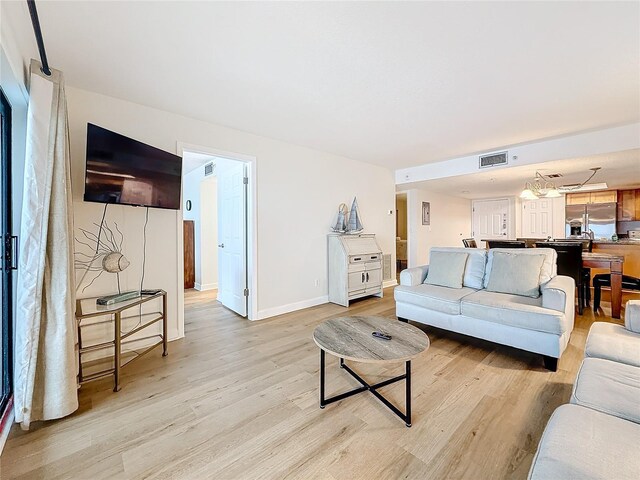 living area with baseboards, visible vents, and light wood finished floors