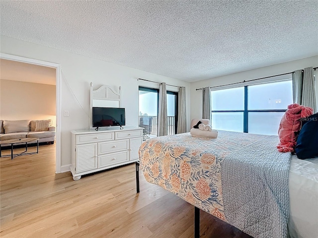 bedroom featuring light wood-type flooring, access to outside, baseboards, and a textured ceiling