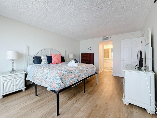 bedroom featuring a textured ceiling, light wood-type flooring, visible vents, and baseboards