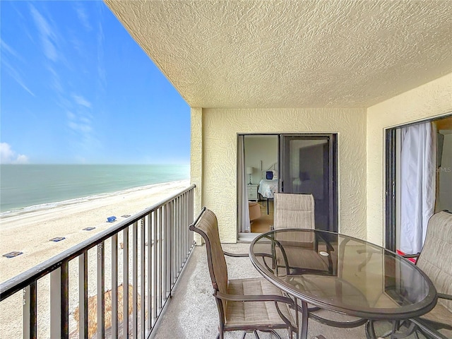 balcony with a water view and a view of the beach